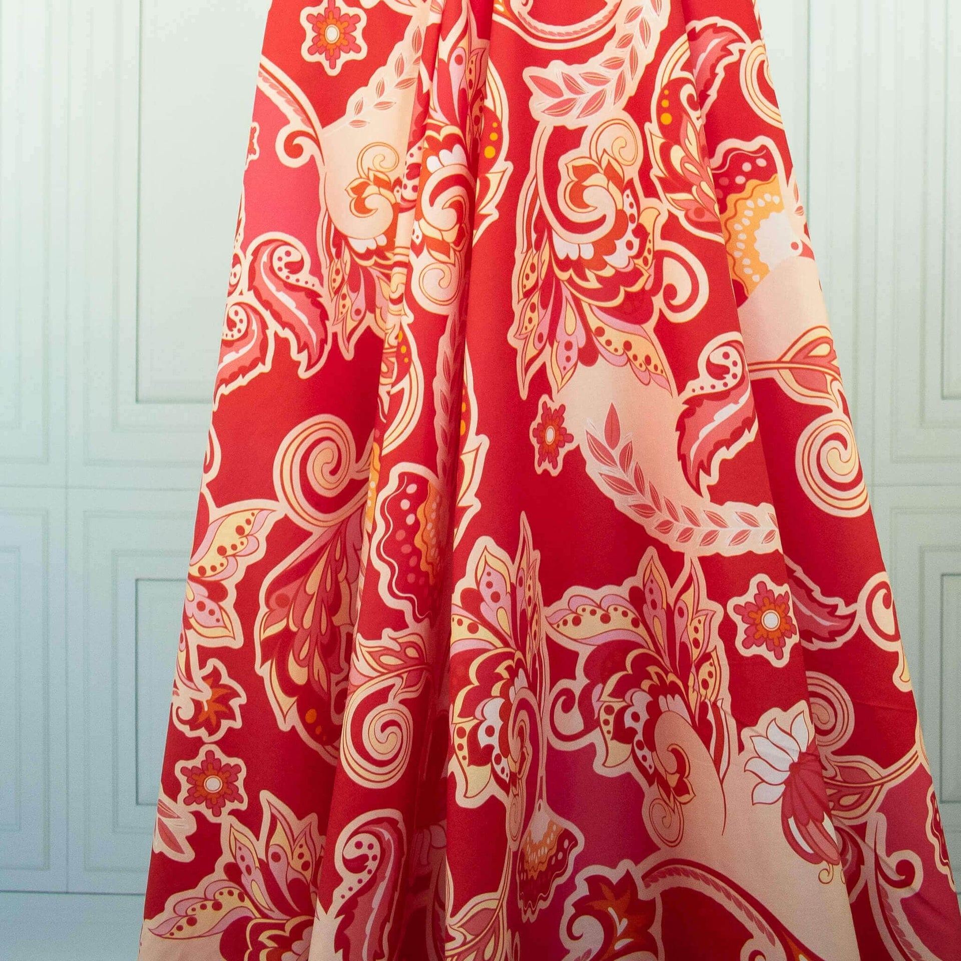 Image of Italian Viscose Coral Red Paisley woven fabric by the yard draped on dress form 