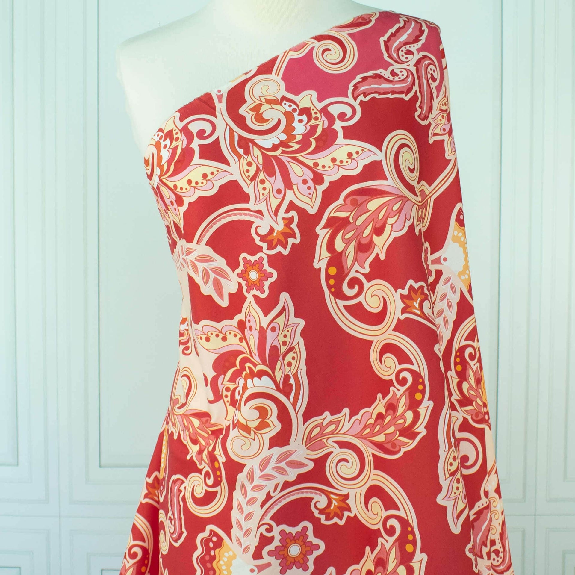 Italian Viscose Coral Red Paisley woven fabric by the yard draped on dress form.
