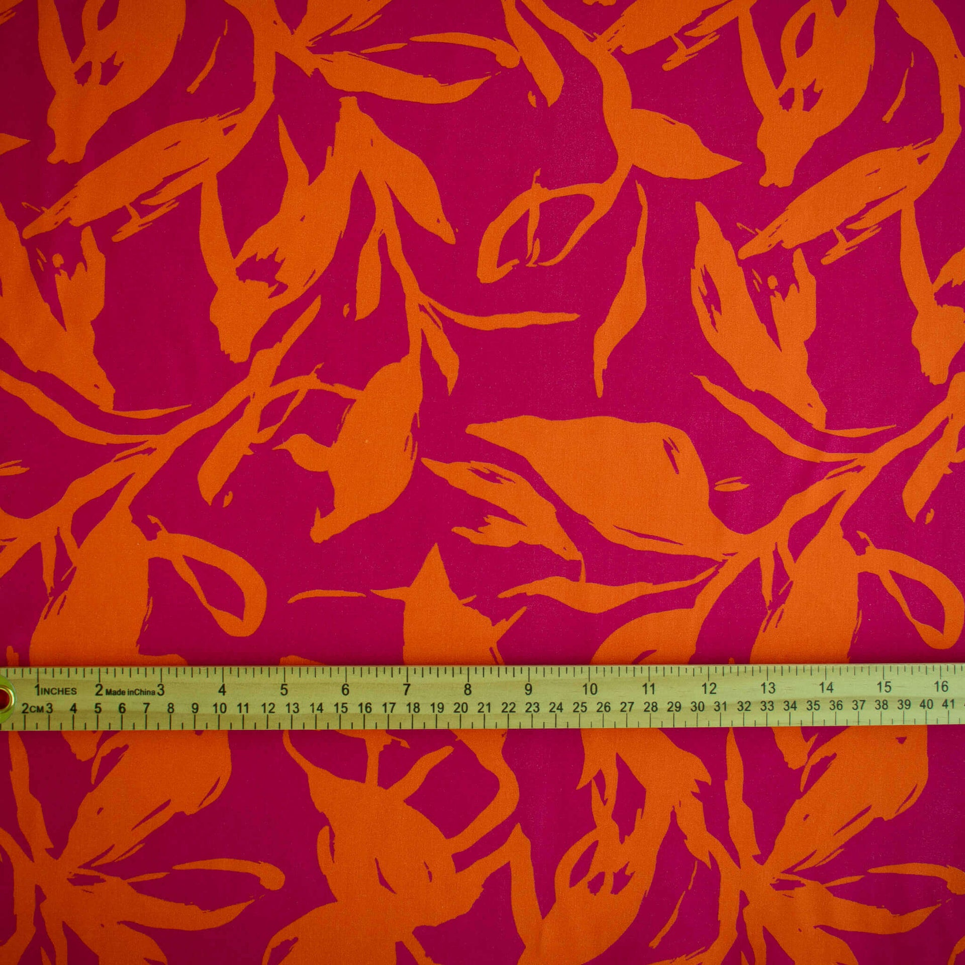 Image of Italian Viscose fabric by the yard in a tropical leaf print demonstrating print scale with ruler.