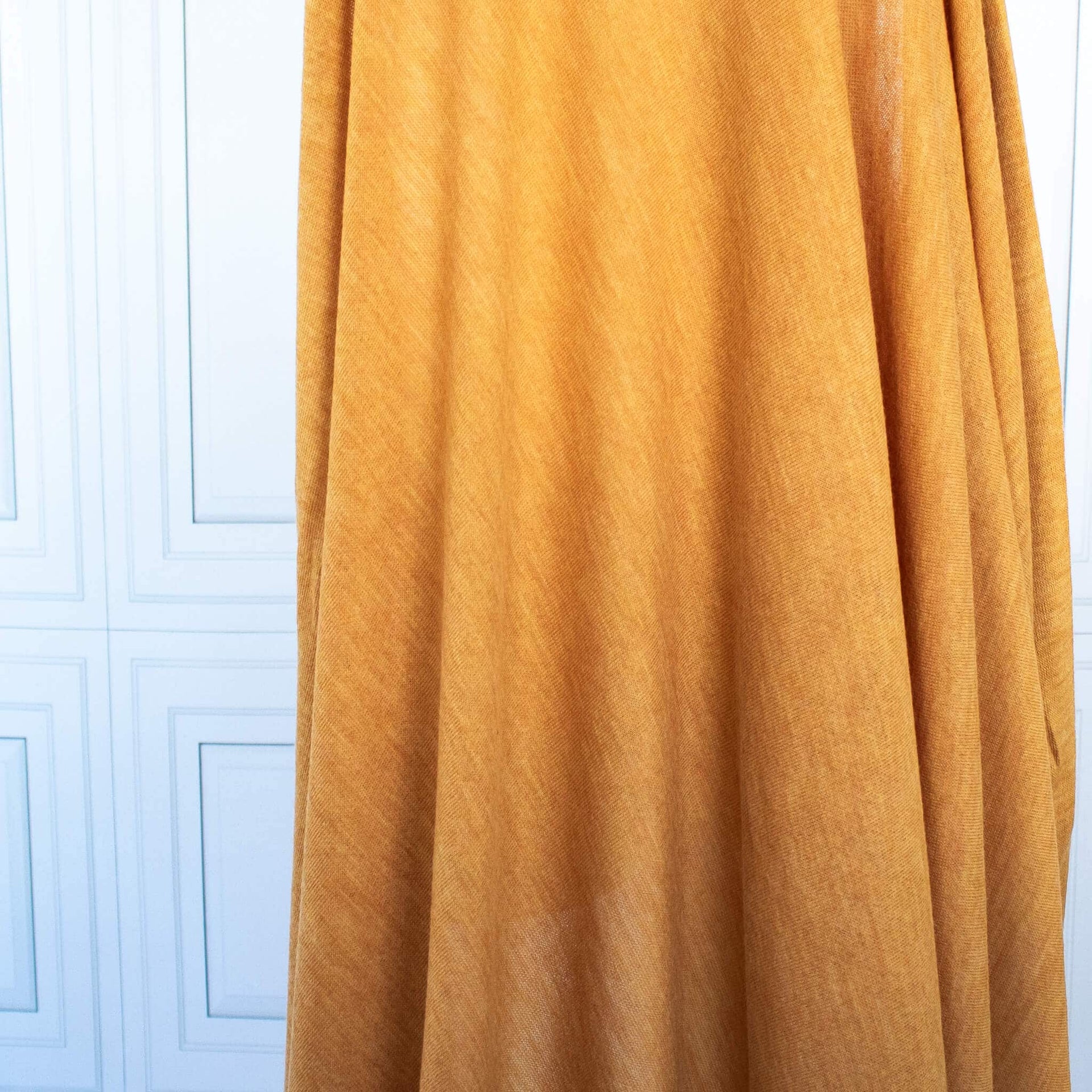 Fine Italian Wool Knit Jersey fabric by the yard in golden saffron. Image of fabric drape.