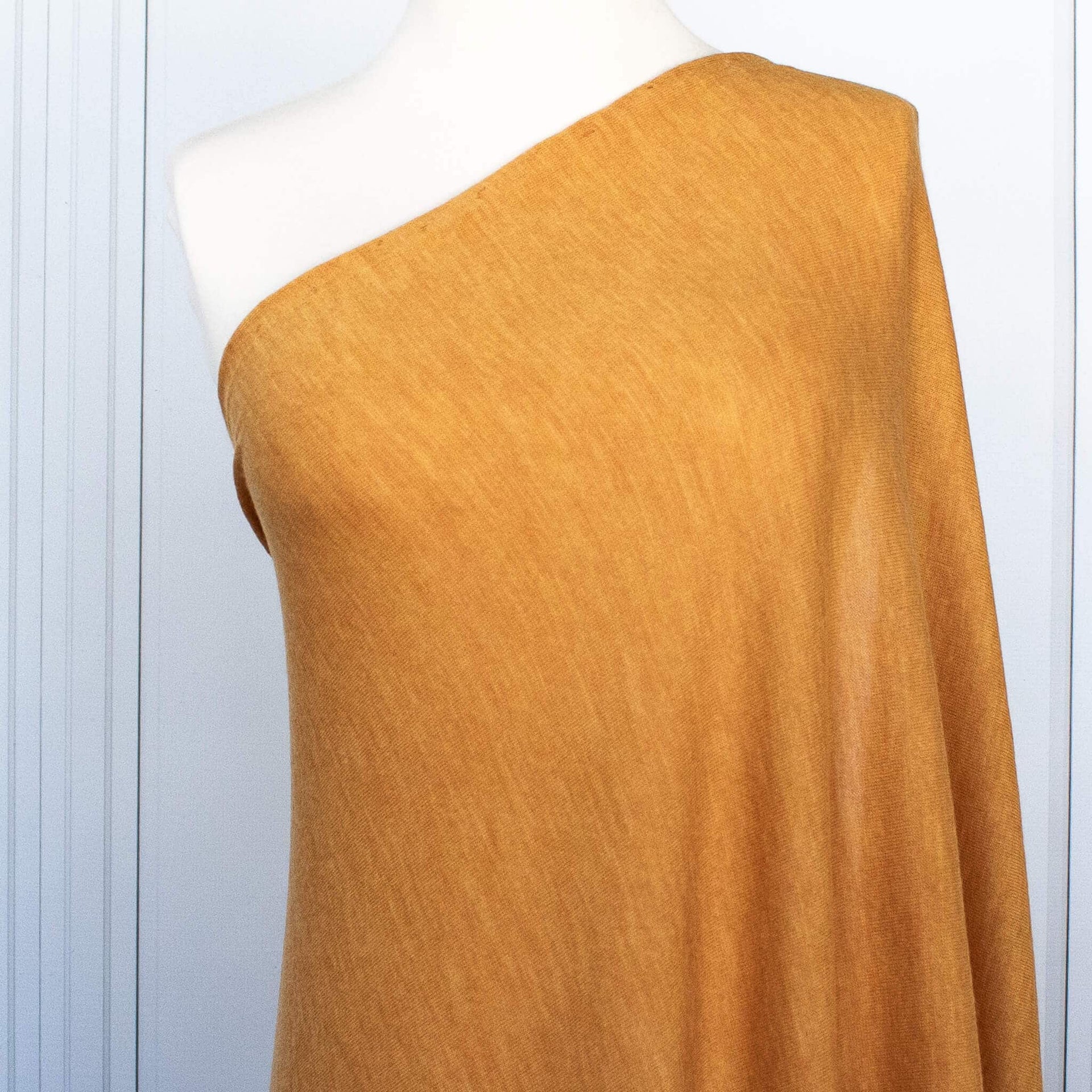Fine Italian Wool Knit Jersey fabric by the yard in golden saffron. Close up of fabric draped on dress form.