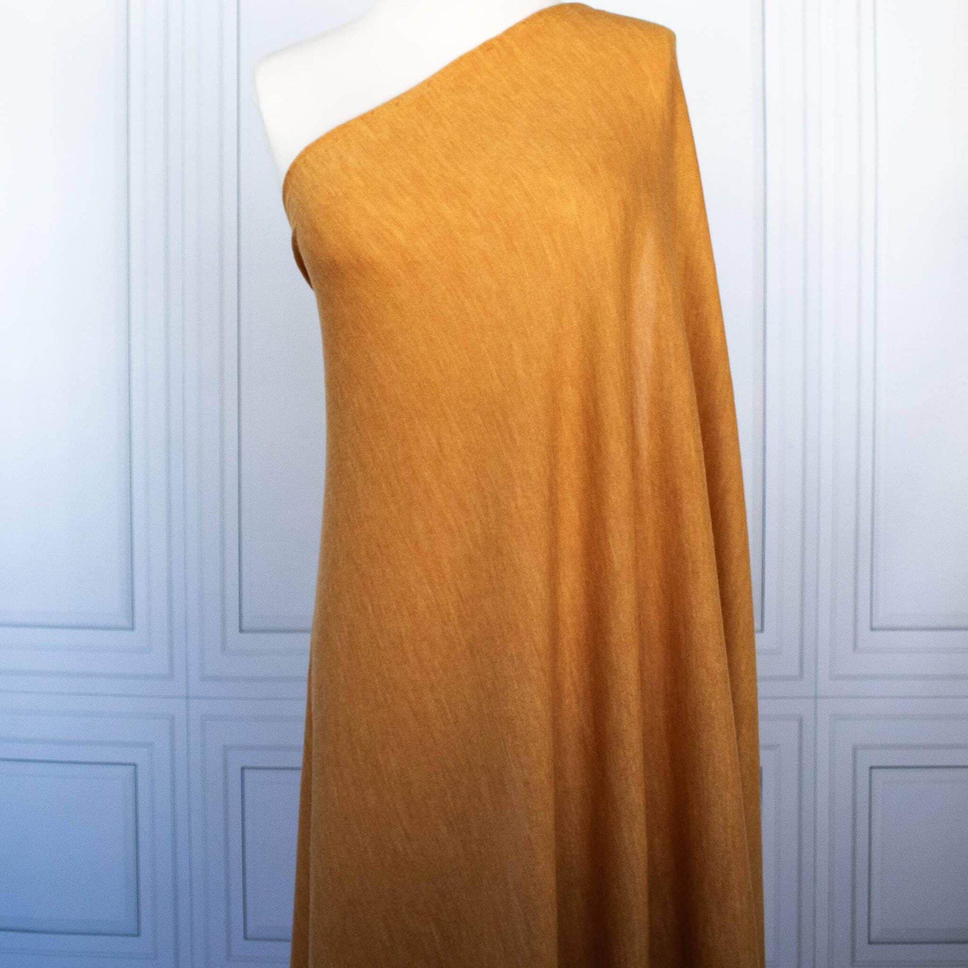 Fine Italian Wool Knit Jersey fabric by the yard in golden saffron draped on dress form.