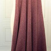 A close-up of Fine Italian Wool/Silk Blend Knit fdraped fabric in a heathered Violet Iris color with subtle multicolored flecks, shown against a white paneled wall background.