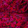 Italian woven viscose crepe fabric by the yard. Beautiful blooms are perfect when you want to add a burst vibrant color! Richly printed in shades of red, pink and lilac with vibrant green leaves set against a black background.  Close of image.
