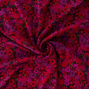 Italian woven viscose crepe fabric by the yard. Beautiful blooms are perfect when you want to add a burst vibrant color! Richly printed in shades of red, pink and lilac with vibrant green leaves set against a black background.  Image of fabric body.