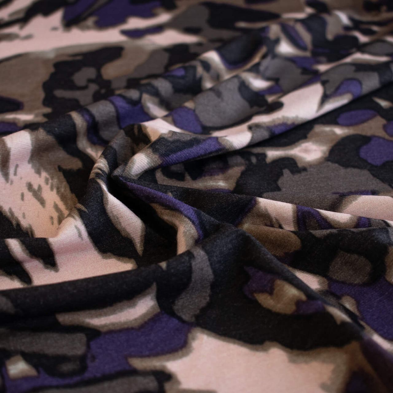 Italian Modern Floral Single Jersey Wool blend fabric by the yard. Gorgeous modern floral print perfect for transitioning to warmer months. This wool blend jersey in shades of brown, light pink, purple and black has a soft hand a beautiful drape. Whether you are creating a T-shirt or something a bit fancier, you're going to love how this fabric feels against your skin. Close up image.