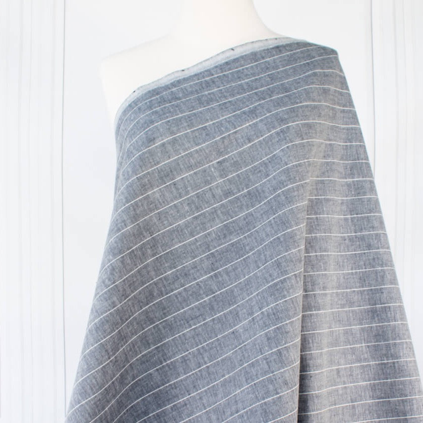 Cotton/Linen Chambray fabric by the yard. On the lighter side of mid-weight, this woven dark navy chambray features a white vertical pinstripe, a nice comfortable hand, and a lovely drape.  Image of fabric draped on dressform.