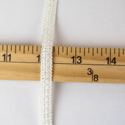 Mokubba Ivory Passenmenterie in soft white close up photo with ruler. Perfect trim to add a couture touch.