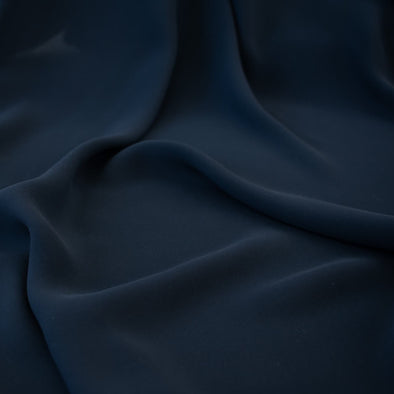 Become a fashionista with this NYC designer 100% silk double georgette Prussian blue fabric by the yard. A designer deadstock fabric that is flowy, with a textured hand, and can be cut on the bias for a stunning top, dress, or skirt! Close up image