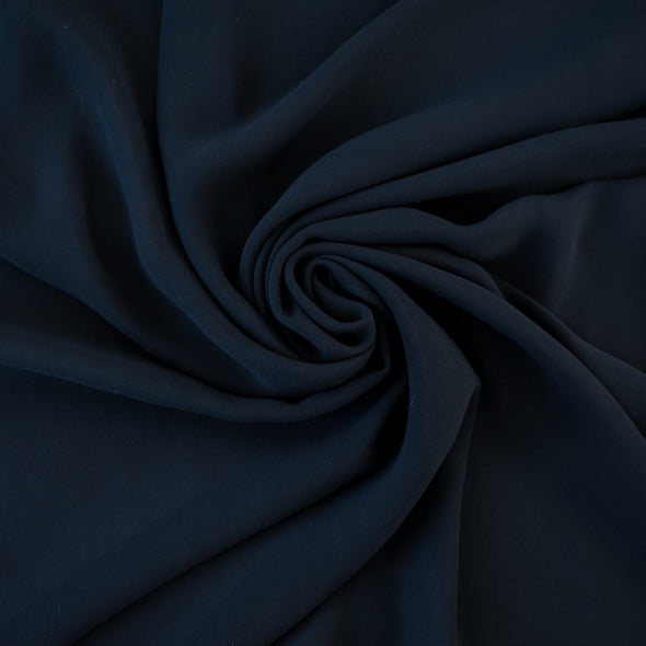 Become a fashionista with this NYC designer 100% silk double georgette Prussian blue fabric by the yard. A designer deadstock fabric that is flowy, with a textured hand, and can be cut on the bias for a stunning top, dress, or skirt!  Image of fabric body.