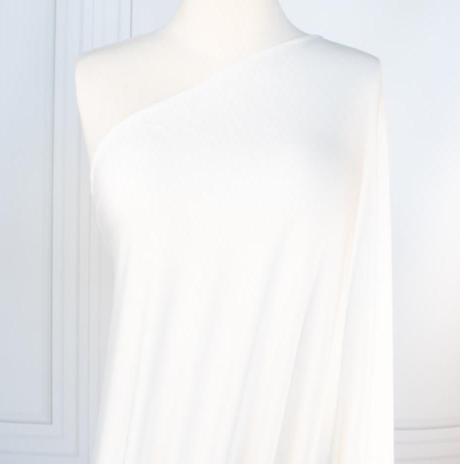 Los Angeles Designer modal jersey knit deadstock fabric by the yard is sustainability at its best. A soft and smooth off-white knit fabric with a cool hand and fluid drape, perfect for a T-shirt, camisole, or loungewear. Image of fabric on dressform.