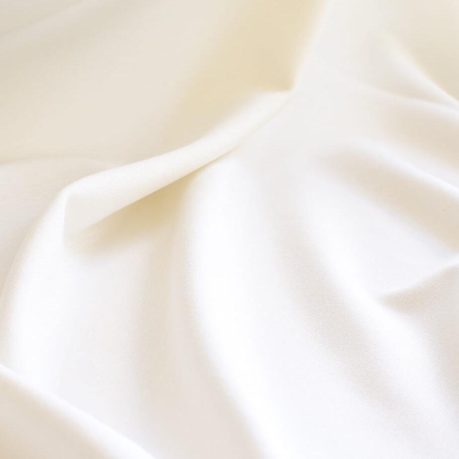 High-End Designer Pearl White Ponte Knit fabric by the yard. This Los Angeles designer has a knack for finding quality fabrics. This designer deadstock Ponte is soft with a nice drape that falls moderately close to the body. You'll fall in love with the comfort! Close up image.
