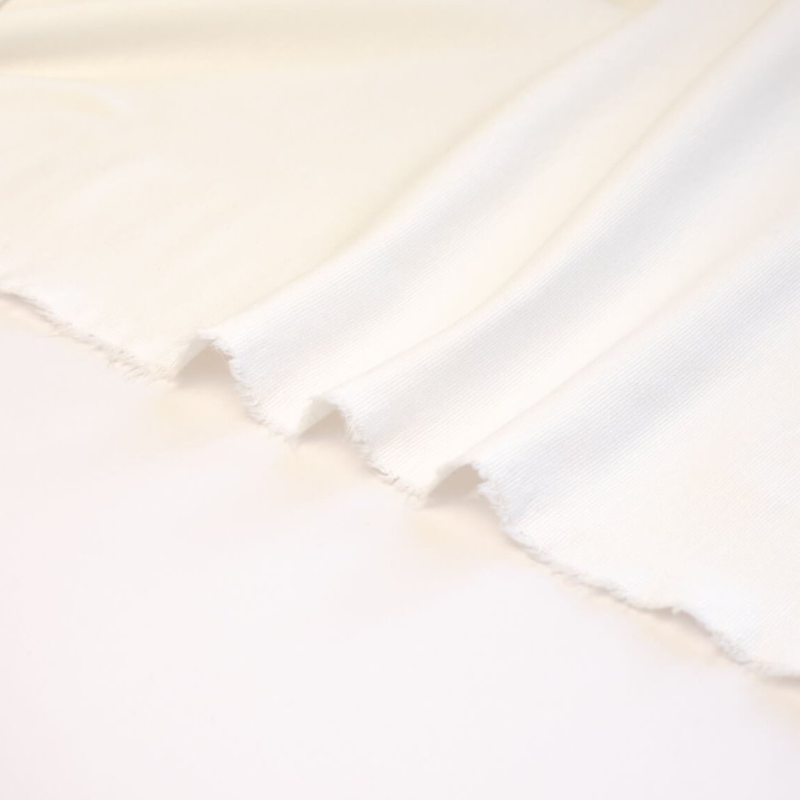 High-End Designer Pearl White Ponte Knit fabric by the yard. This Los Angeles designer has a knack for finding quality fabrics. This designer deadstock Ponte is soft with a nice drape that falls moderately close to the body. You'll fall in love with the comfort! Image of selvedge.