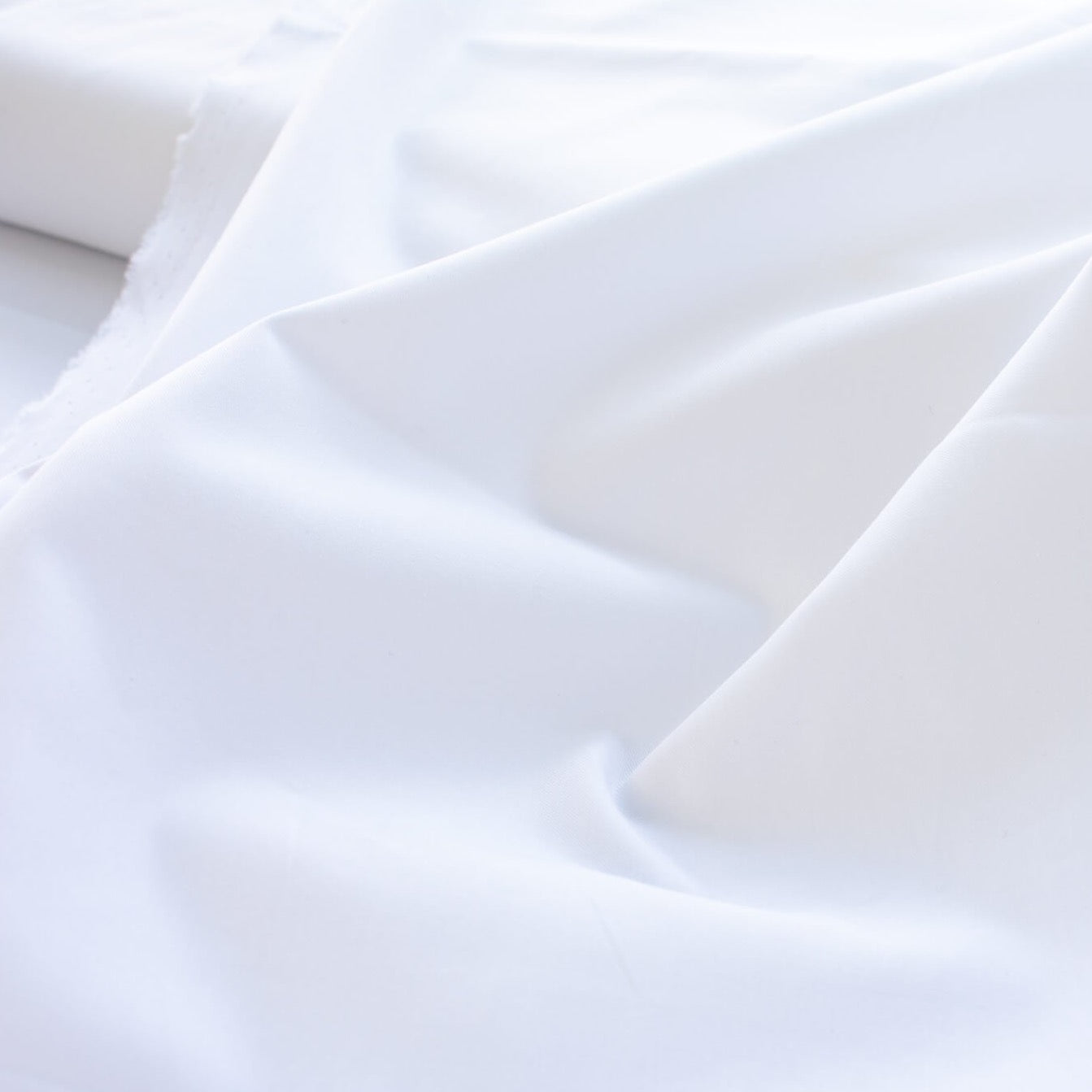 High-End Designer White Cotton Fine Twill fabric by the yard. Simple elegance at its finest from a Los Angeles designer that has a knack for finding luxurious fabrics. Close up of fabric.