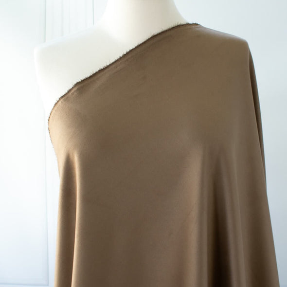 Take your projects up a notch with our Faux Suede Knit fabric by the yard in a soft brown we call "Haute Chocolate". Luxuriously smooth and endlessly fabulous, it's the perfect fabric to add a subdued edge to your "Haute" look! Image of fabric draped on dressform