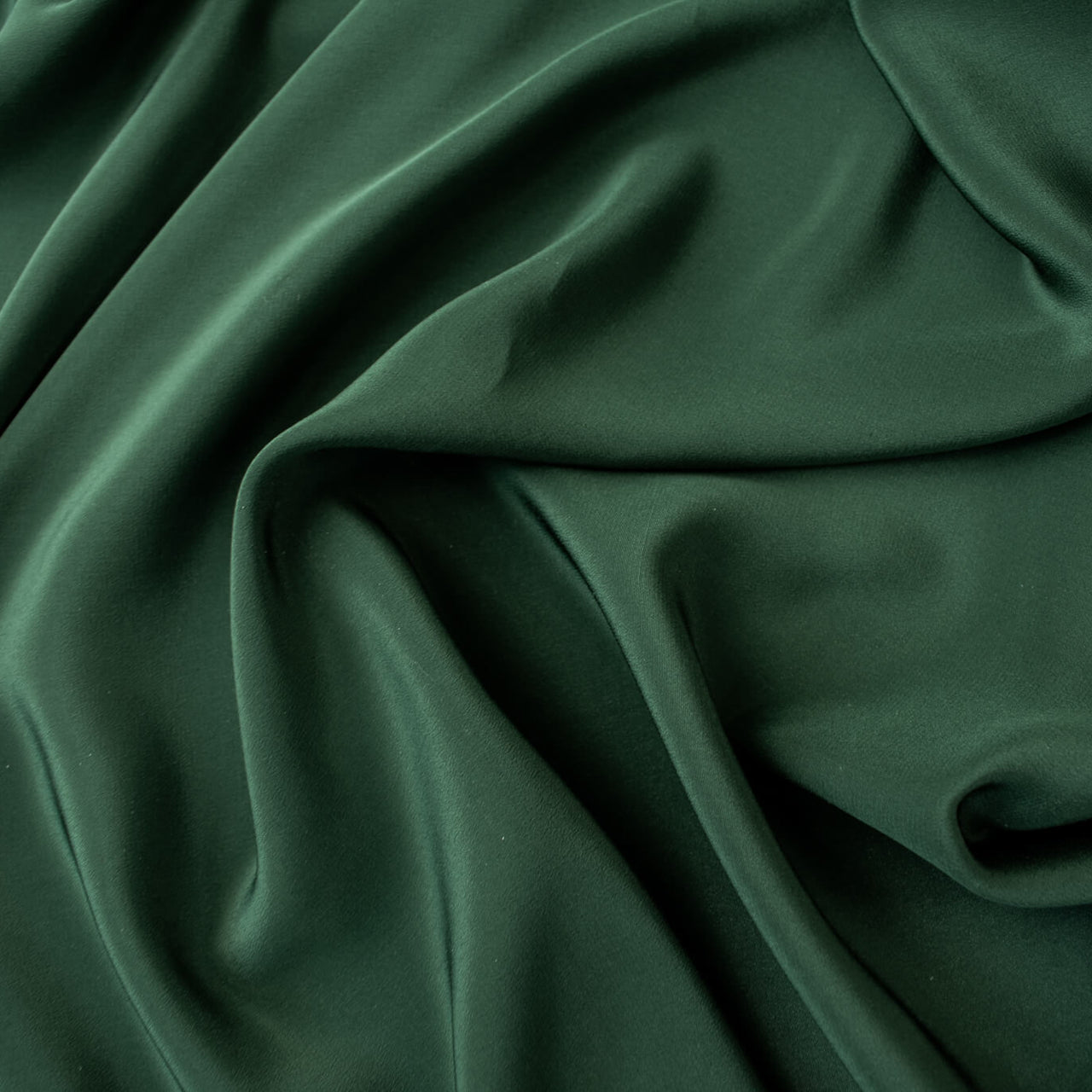 00% Silk Crepe de Chine fabric by the yard in Fern Green. Soft and fluid, this semi-textured fabric offers a beautiful drape and the luxury of silk.  Close up image.
