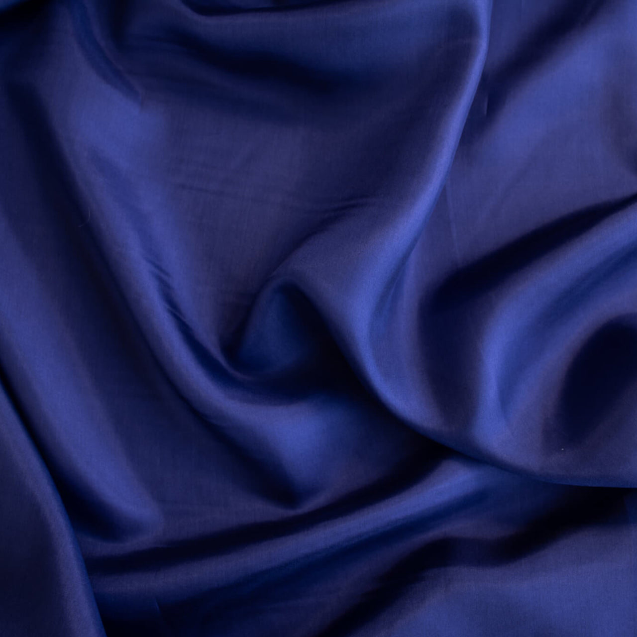 'Violet' Royal Blue 100% China Silk fabric by the yard. Lightweight and translucent, its soft hand and delicate drape make it perfect for tops and especially for lining your couture hand-made garments. Made from 100% silk, this fabric is sure to add a touch of luxury to your sewing project. Close up image.