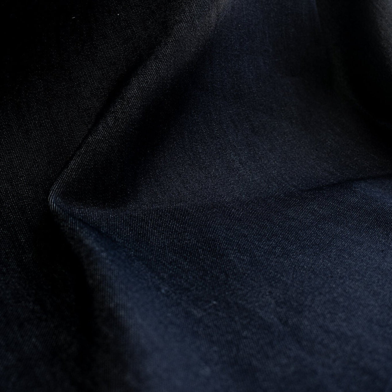 Get the perfect blend of comfort and style with our Midnight Navy Cotton Stretch Denim Twill fabric by the yard.  A denim you can dress up with its deep rich dark blue color and crisp, semi-textured hand. Close up image.