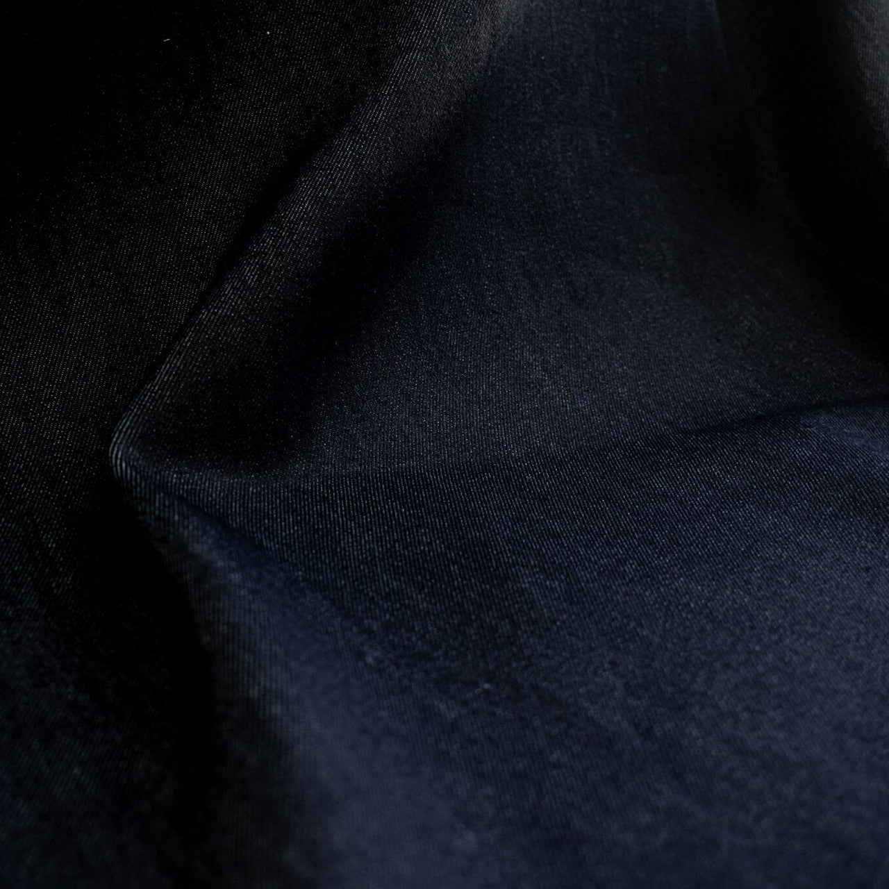 Get the perfect blend of comfort and style with our Midnight Navy Cotton Stretch Denim Twill fabric by the yard. &nbsp;A denim you can dress up with its deep rich dark blue color and crisp, semi-textured hand. Close up image.