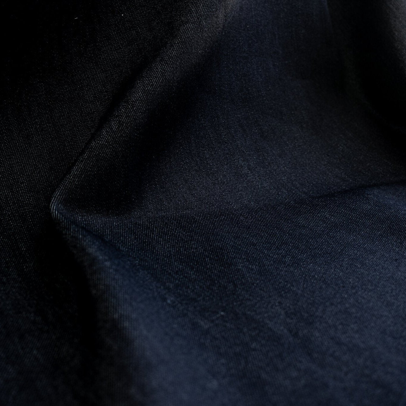 Get the perfect blend of comfort and style with our Midnight Navy Cotton Stretch Denim Twill fabric by the yard. &nbsp;A denim you can dress up with its deep rich dark blue color and crisp, semi-textured hand. Close up image.