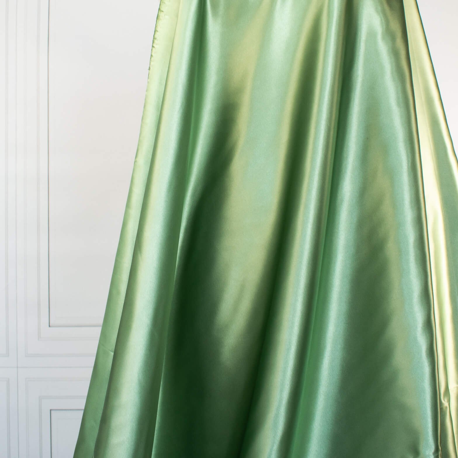 NYC Designer Polyester Satin designer deadstock fabric by the yard. Shimmery satin in a serene spring green is sophisticated and eye catching! &nbsp;This opaque, tightly woven fabric falls moderately away from the body. Image of fabric drape.