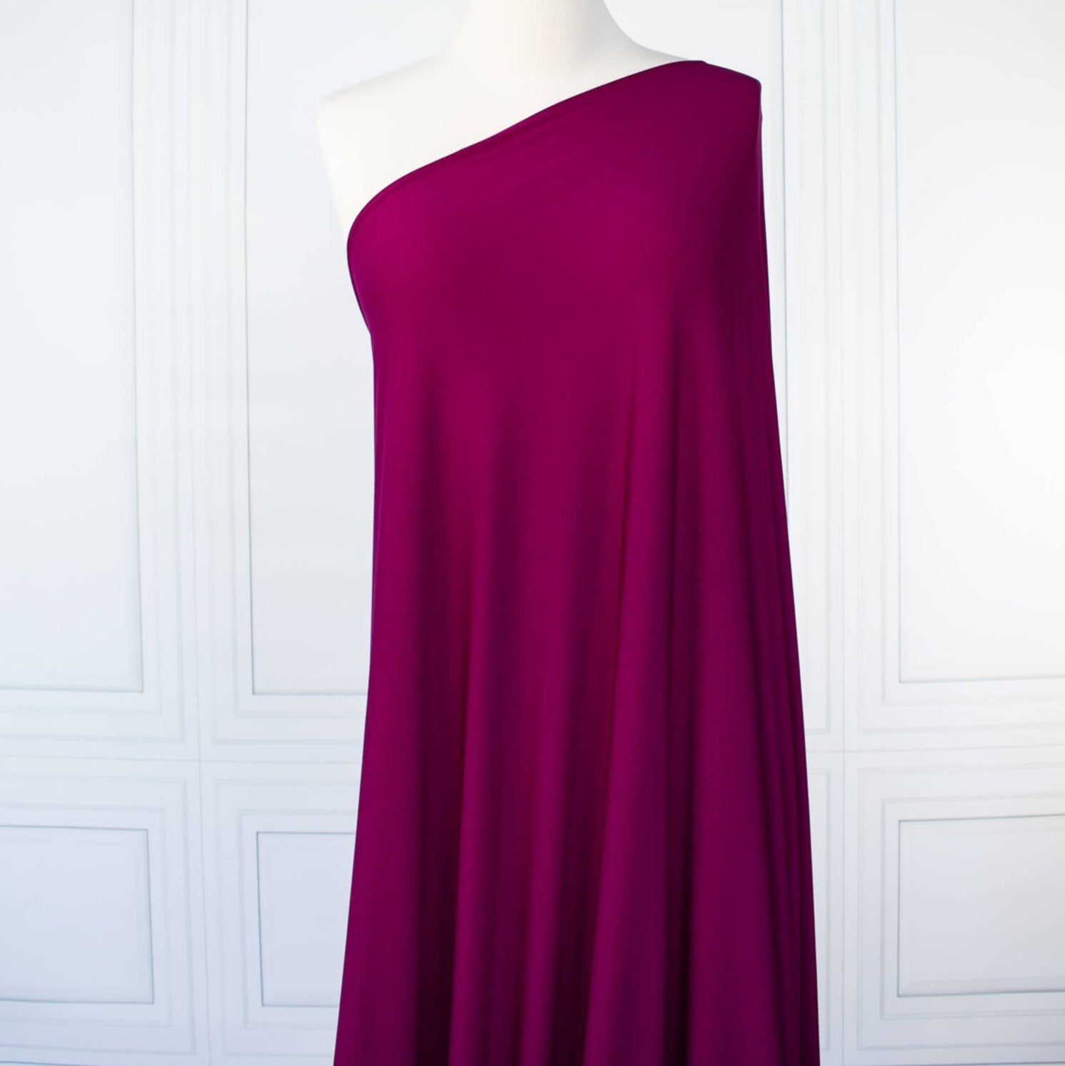 Famous Designer Poly/Spandex ITY Knit in 'Berry Rich'! This designer deadstock fabric by the yard boasts a rich berry color that is sure will elevate any project. Its smooth hand and elegant drape is a must have for comfort and style. Long image of fabric draped on dressform.