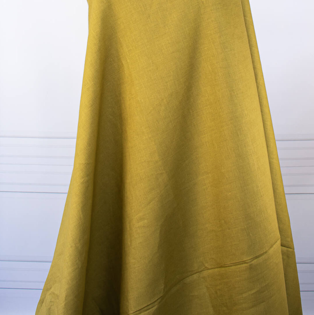 100% Linen Mid-Weight Woven fabric by the yard in a&nbsp;gorgeous golden green is a stunner and perfect for warmer weather. This plain weave linen is soft and has a crisp semi-textured hand. Create a lovely Jacket, Pant, Tunic or Vest! Image of fabric drape.