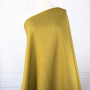100% Linen Mid-Weight Woven fabric by the yard in a&nbsp;gorgeous golden green is a stunner and perfect for warmer weather. This plain weave linen is soft and has a crisp semi-textured hand. Create a lovely Jacket, Pant, Tunic or Vest! Long view image of fabric draped on dressform.