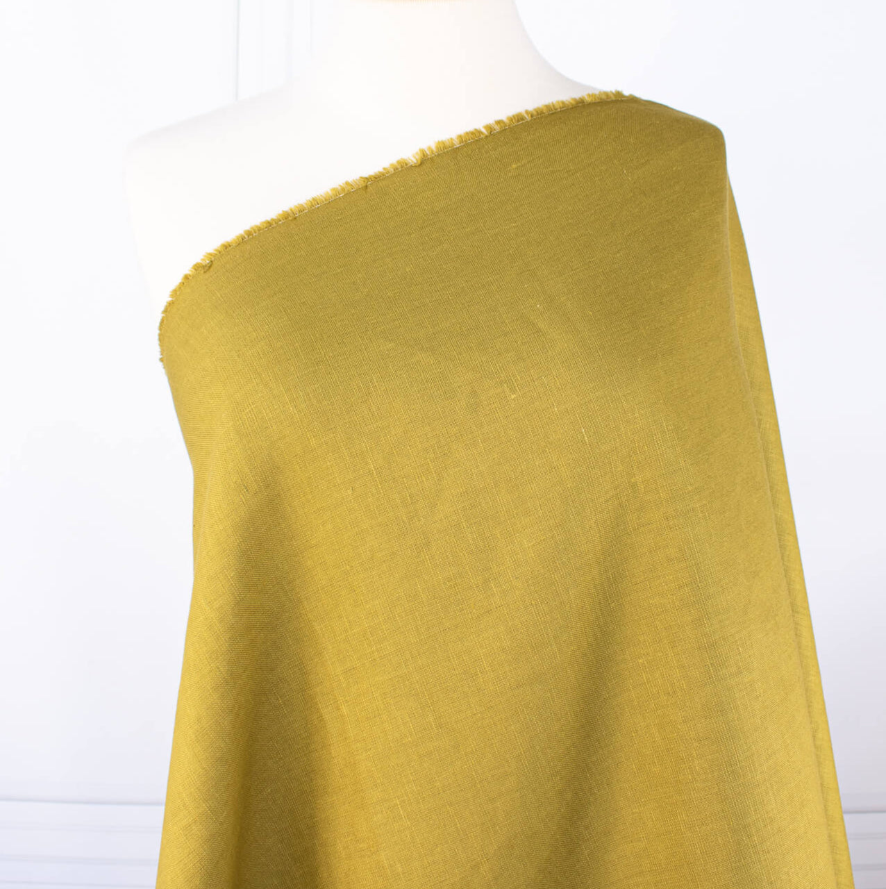 100% Linen Mid-Weight Woven fabric by the yard in a&nbsp;gorgeous golden green is a stunner and perfect for warmer weather. This plain weave linen is soft and has a crisp semi-textured hand. Create a lovely Jacket, Pant, Tunic or Vest! Image of fabric draped on dressform.