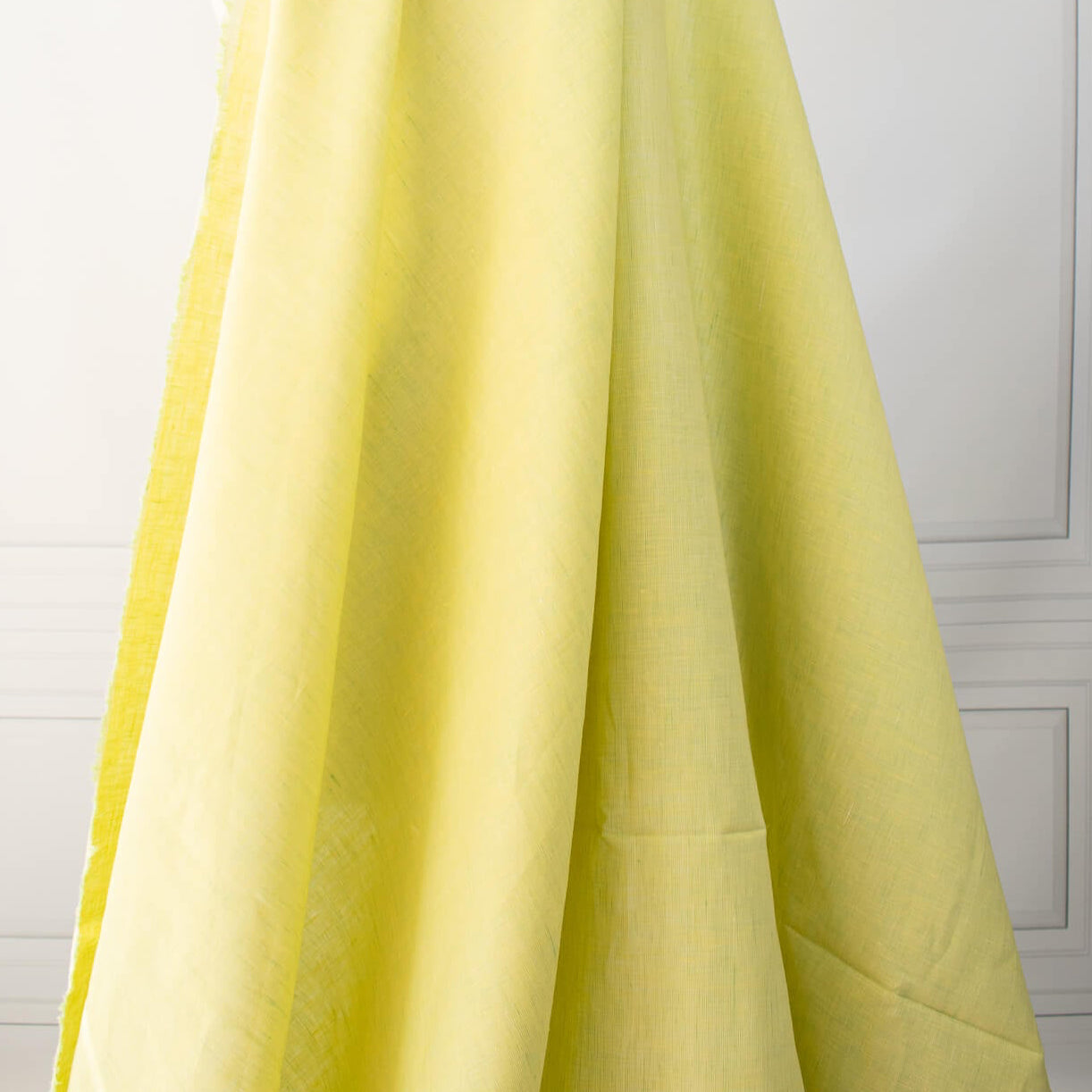 Made of 100% linen, this shirt-weight fabric features a gentle blend of spring green, white, and soft yellow tones, perfect for a stylish shirt, dress or skirt. Enjoy the lightweight, soft semi-crisp hand of this cross-dyed, woven fabric. Image of fabric drape.