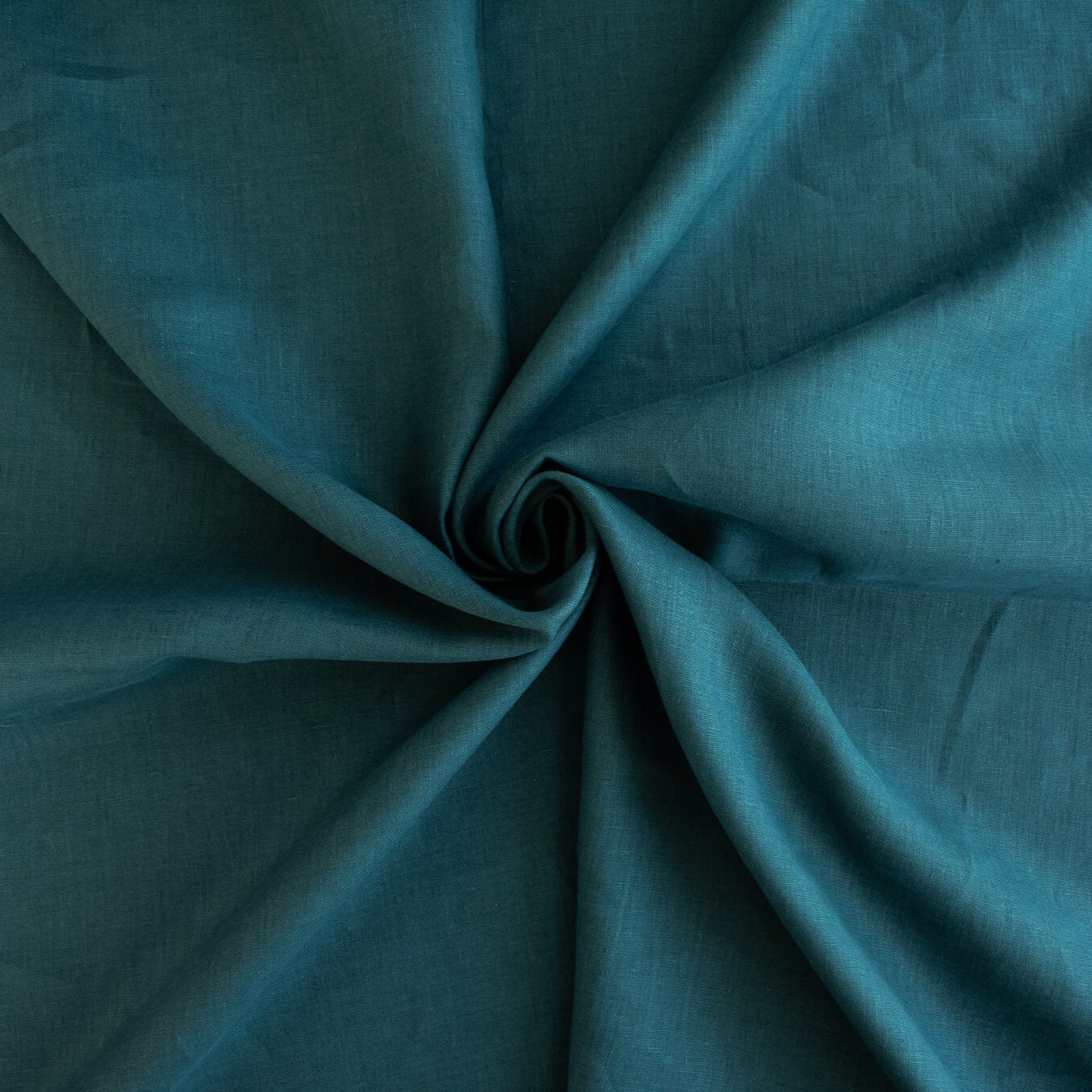 Harbor Blue 100% Linen shirt-weight woven fabric by the yard. Enjoy the soft and crisp hand and beautiful harbor blue hue that is sure to be a fantastic color to wake up your neutral pieces. Image of fabric fullness.