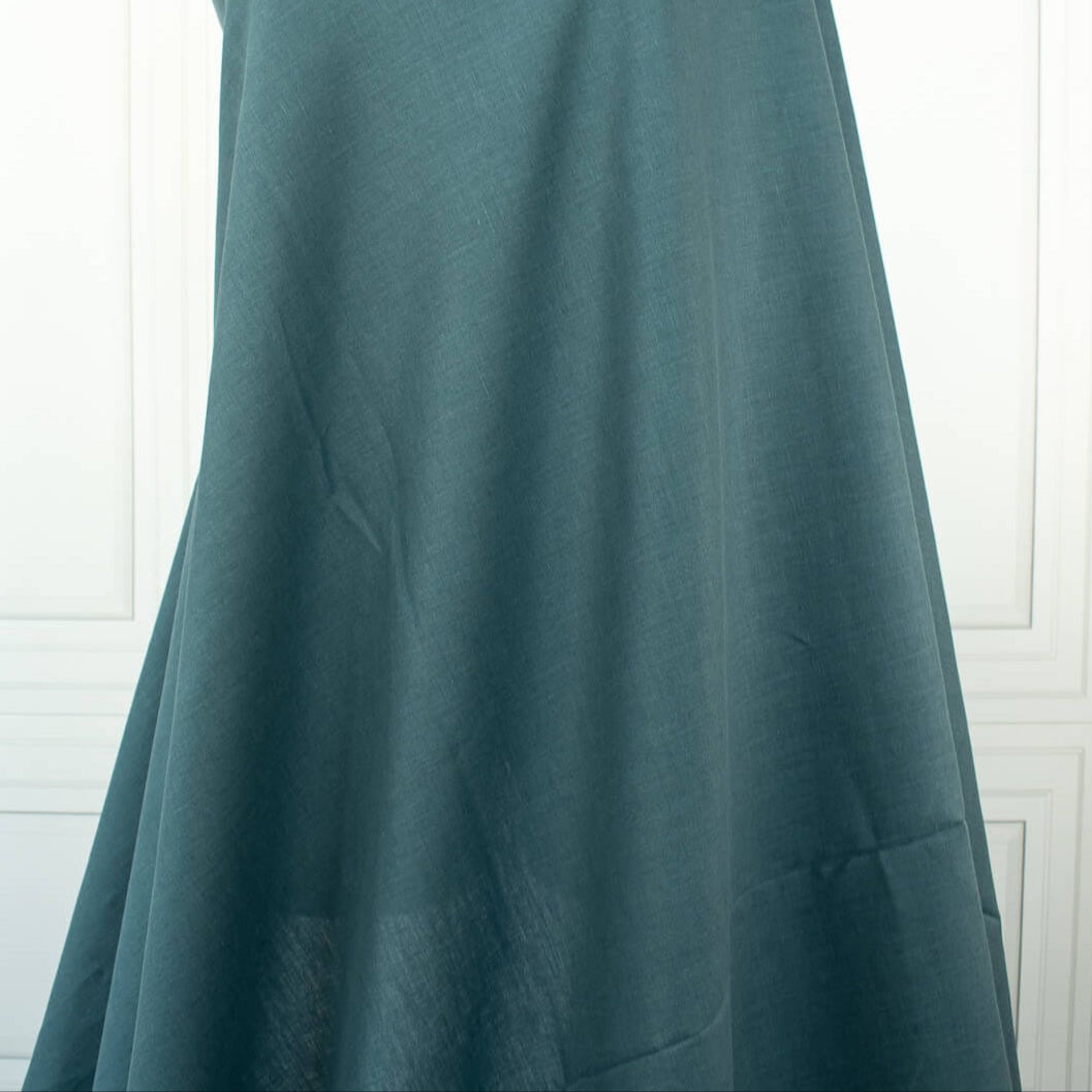 Harbor Blue 100% Linen shirt-weight woven fabric by the yard. Enjoy the soft and crisp hand and beautiful harbor blue hue that is sure to be a fantastic color to wake up your neutral pieces. Image of fabric drape.