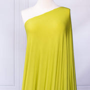 Close up of Designer citrus green 4-way stretch knit fabric draped on dressform.