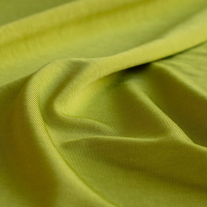 Close-up of citrus green designer 4-way stretch knit fabric with folds
