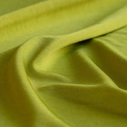 Close-up of citrus green designer 4-way stretch knit fabric with folds