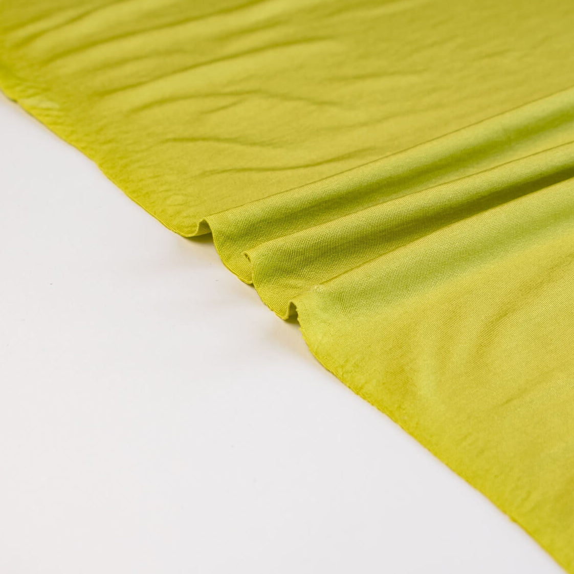 Close-up of citrus green designer 4-way stretch knit fabric on a white background