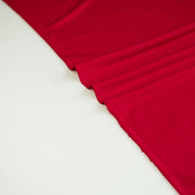 Close-up of warm red ITY jersey fabric with folds. on a white background