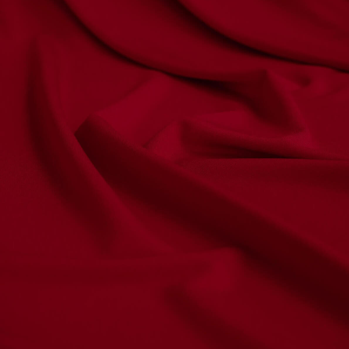 Close-up of warm red ITY jersey fabric with folds.