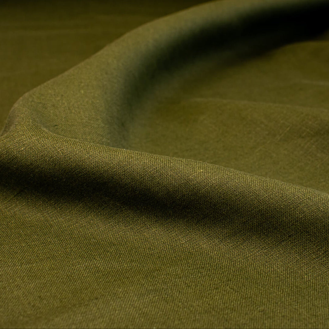 This stunning deep green 100% Linen shirtweight fabric by the yard is sure to become a wardrobe staple. A soft crisp hand and a drape that falls moderately away from the body is perfect for your next linen project. Close up image.
