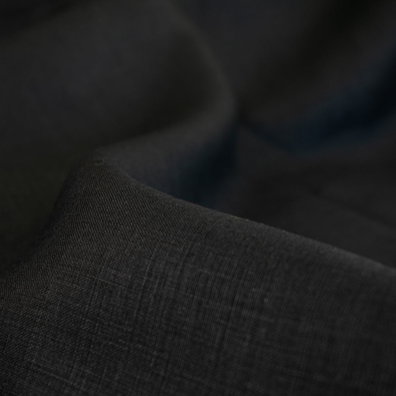 Italian, rich black 100% Linen fabric by the yard in a lovely mid-weight. The soft, crisp, and semi-textured hand of this fabric is perfect for creating sophisticated vests, dresses, suits, and skirts. This breathable fabric is perfect for warmer weather, making it a must-have for any fashion enthusiast. Close up image of fabric weave.