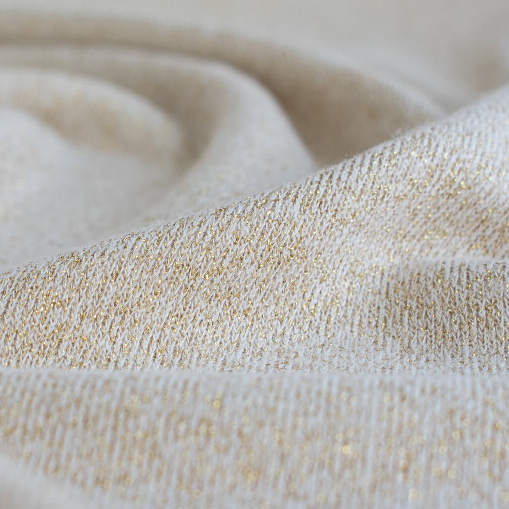 Close up of knit of  Designer White and Gold Metallic  Sweater knit fabric by the yard. 