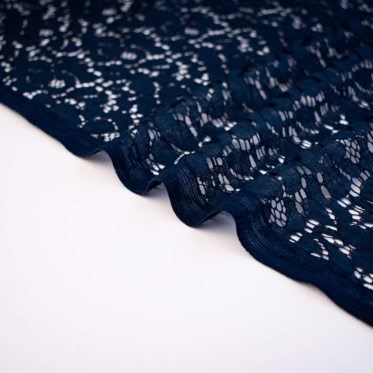 Close-up of dark blue lace fabric on a white background