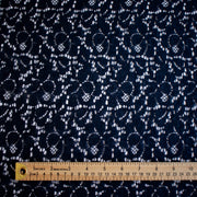 Navy blue fabric with lace pattern and a ruler at the bottom for scale.