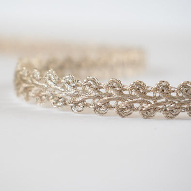 This stunning vintage gimp trim is the perfect addition to any couture garment. Our narrow trim is crafted from a mix of silver and champagne gold metallic threads, making it a designer's dream. A timeless piece, this trim is sure to elevate any project with its timeless charm. Close up.