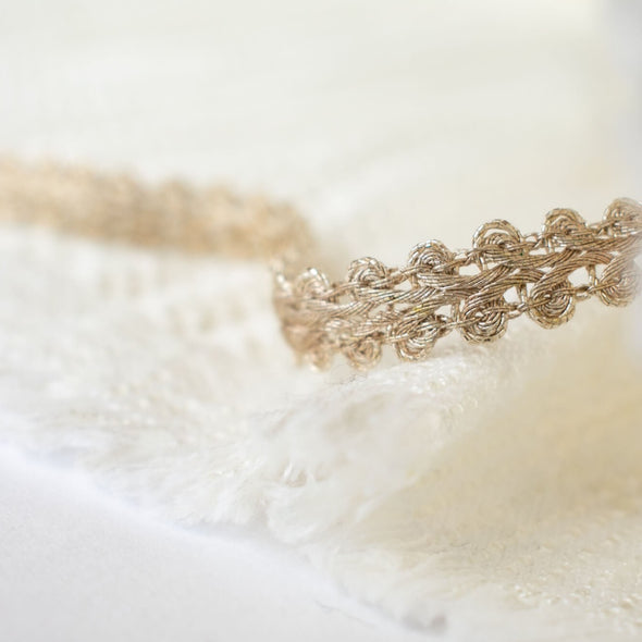 This stunning vintage gimp trim is the perfect addition to any couture garment. Our narrow trim is crafted from a mix of silver and champagne gold metallic threads, making it a designer's dream. A timeless piece, this trim is sure to elevate any project with its timeless charm. Pictured with boucle fabric for display purposes only. Boucle sold separately.