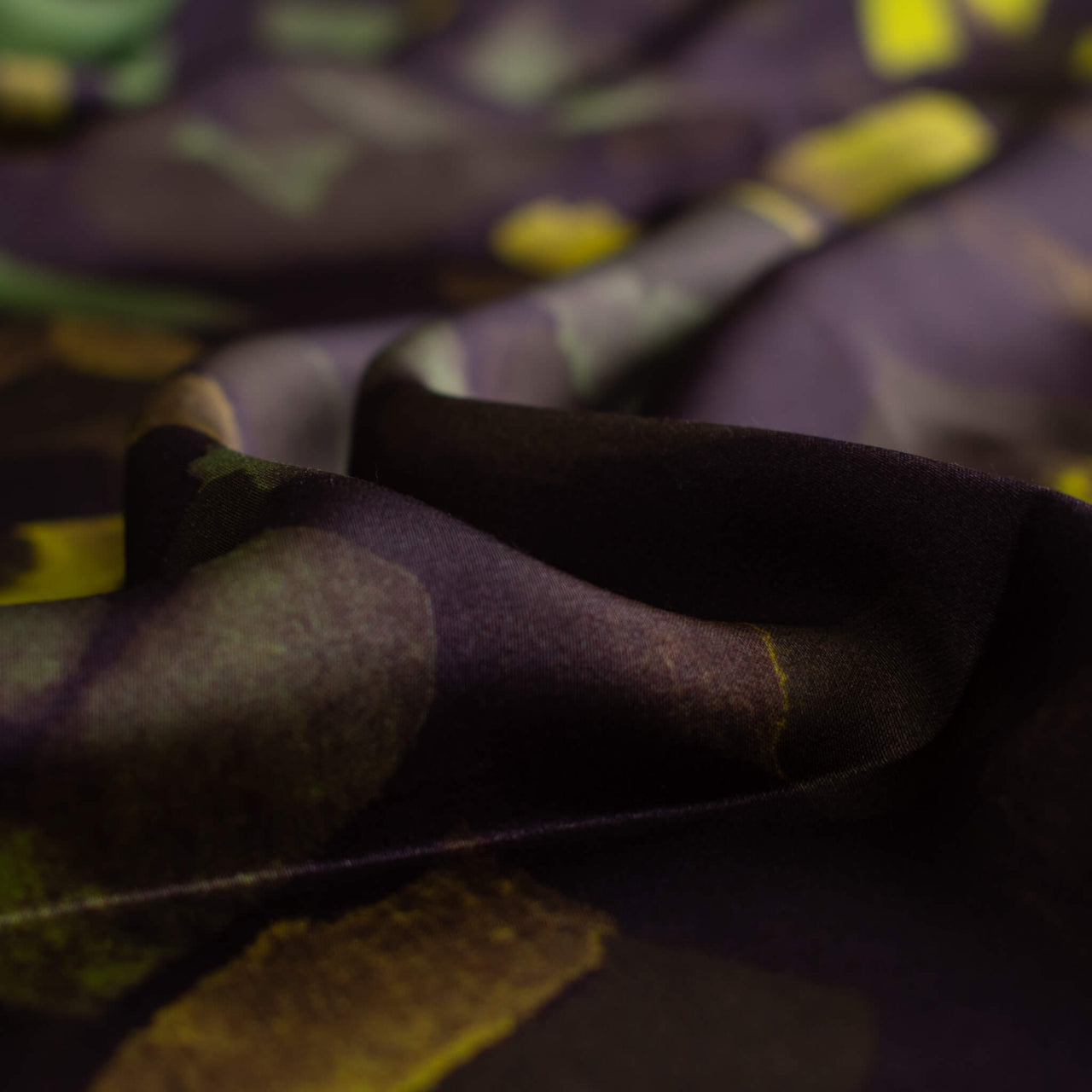 A close-up image of  Italian viscose sateen  fabric by the yard in deep eggplant adorned with modern abstract brushstrokes in olive, fern green, and golden yellow