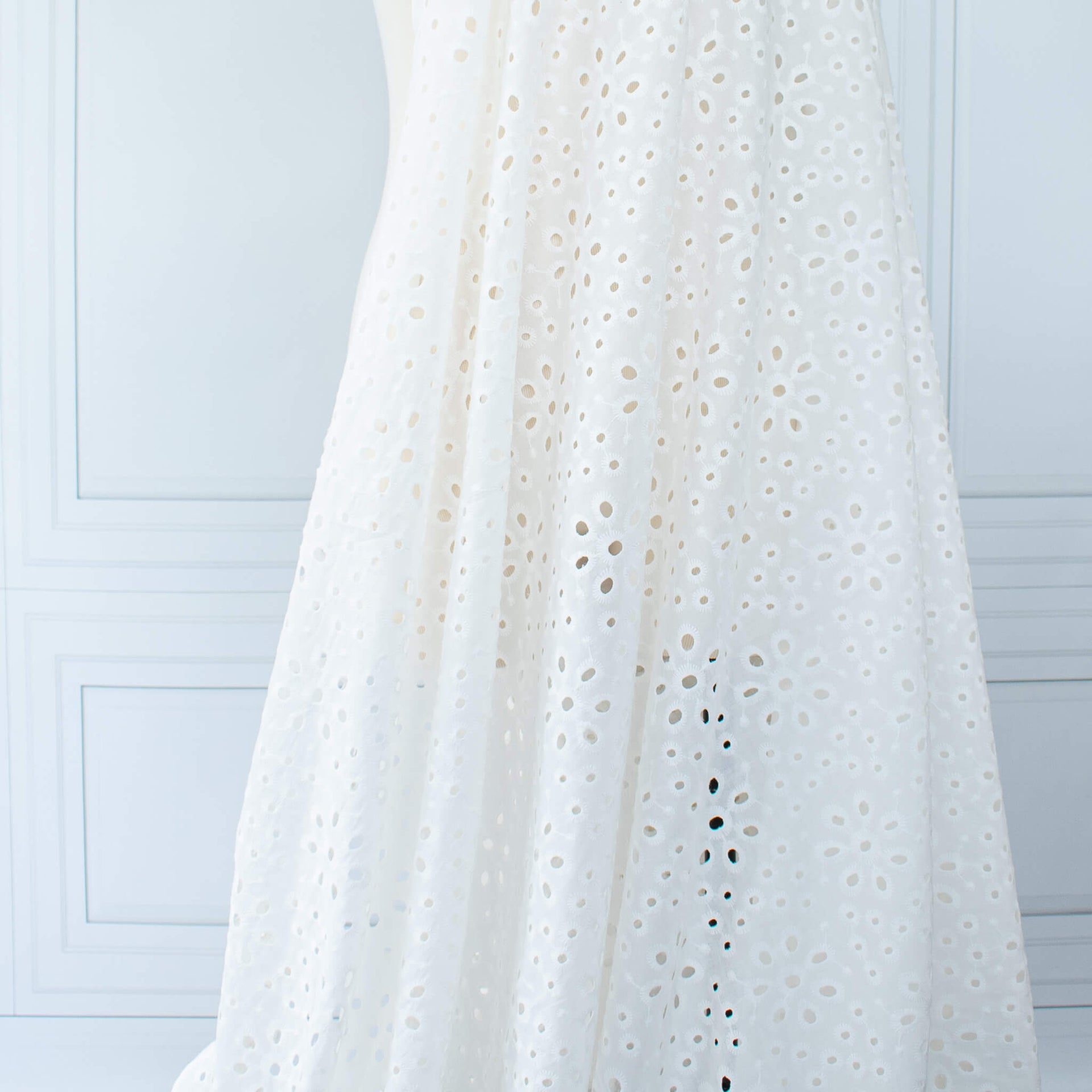 Image of  Italian Cotton San Gallo Lace in soft white, a delicate broderie anglaise fabric draped on dress form.