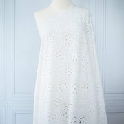 Image of  Italian Cotton San Gallo Lace in soft white, a delicate broderie anglaise fabric draped on dress form.