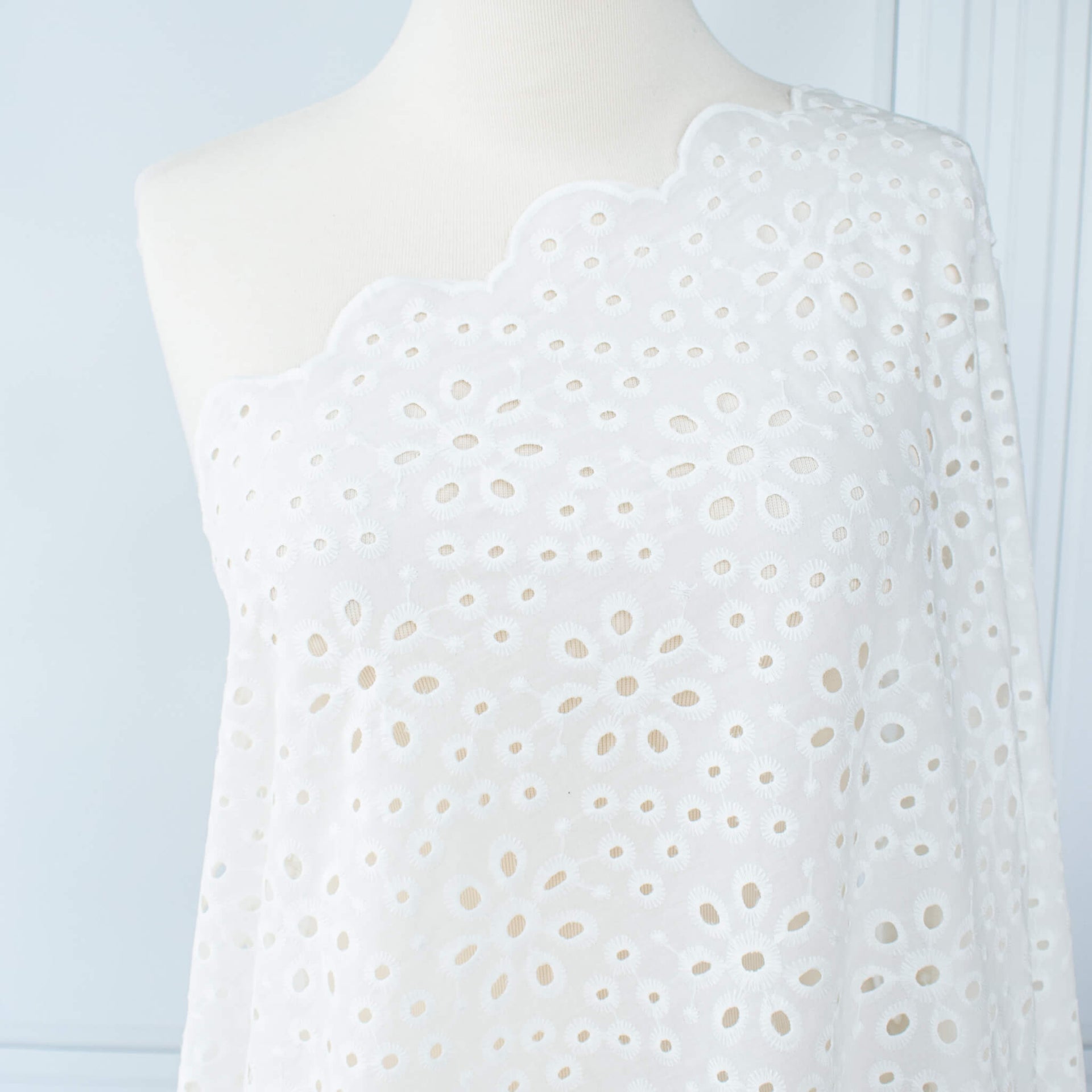 Image of  Italian Cotton San Gallo Lace in soft white, a delicate broderie anglaise fabric draped on dress form.