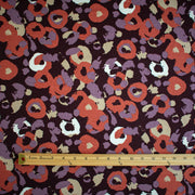 A close-up of  Italian Cotton Jersey Warm Abstract Print fabric with a wooden ruler along the bottom edge for scale.